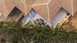 An aerial view of a resort with a geometric roof structure, palm trees, and outdoor seating areas. - Holidays in Porto Santo - Casa do Ribeiro Salgado (Porto Santo)