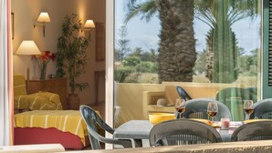 A room with a bed, bedside lamps, a potted plant, and a window with a view of palm trees. - Holidays in Porto Santo - Casa do Ribeiro Salgado (Porto Santo)