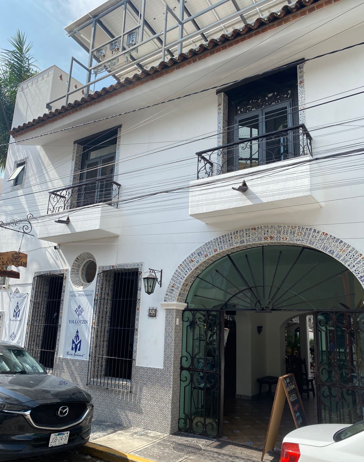 Un immeuble de deux étages doté d’une façade recouverte de tuiles, d’un balcon et d’une grande entrée en arc de cercle.