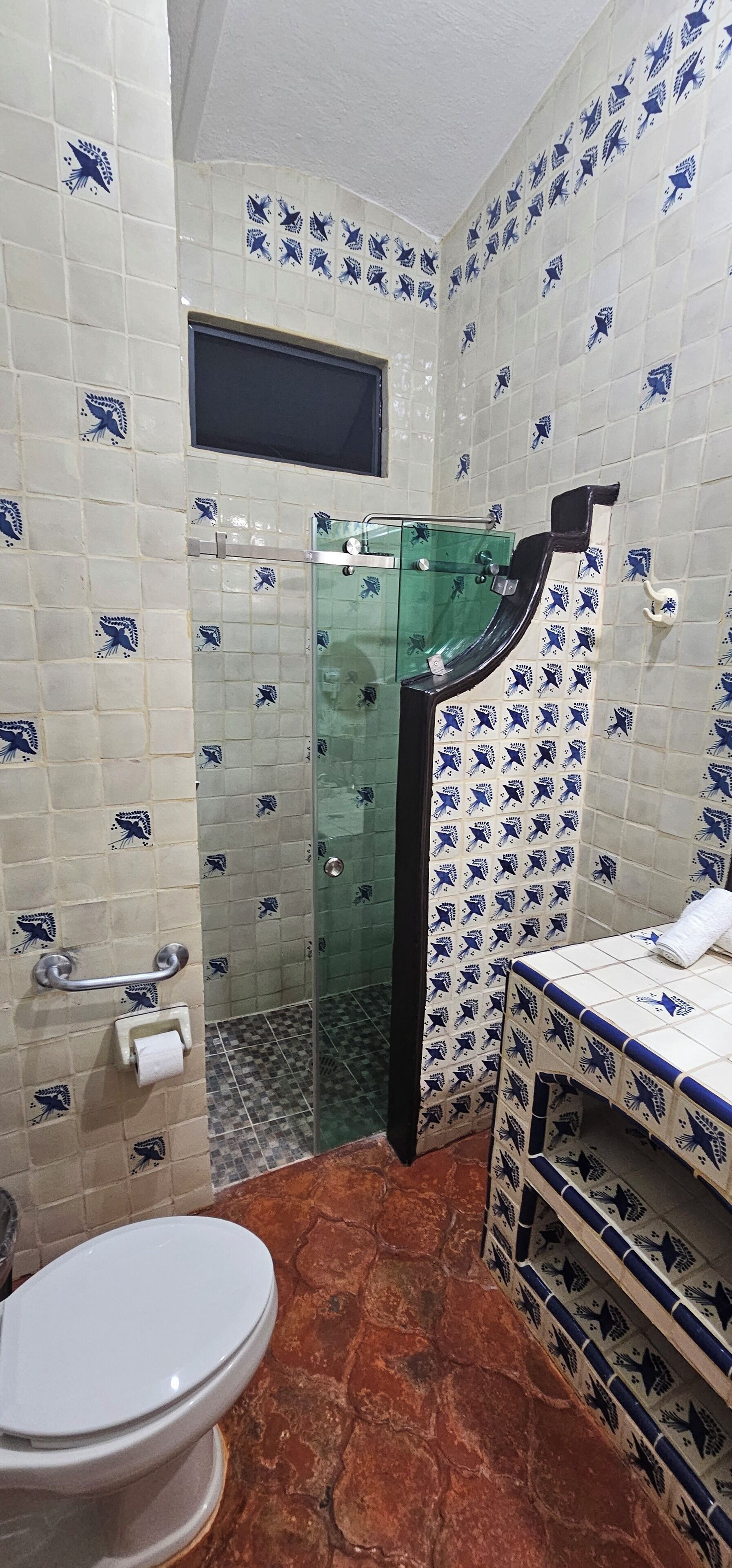 Un baño con inodoro, cabina de ducha de vidrio y lavabo con espejo.