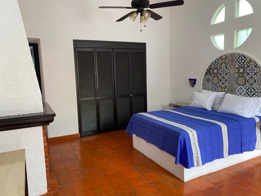 Un dormitorio con cama, ventilador de techo, armario y cabecera estampada.