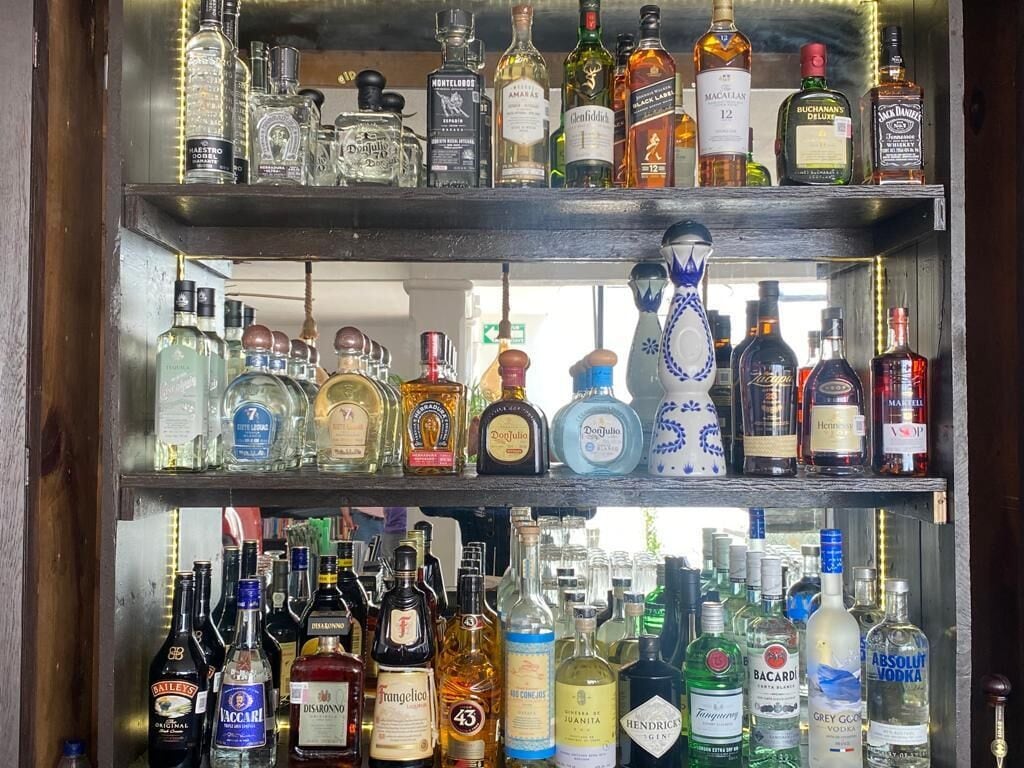 A bar with multiple shelves stocked with various liquor bottles.