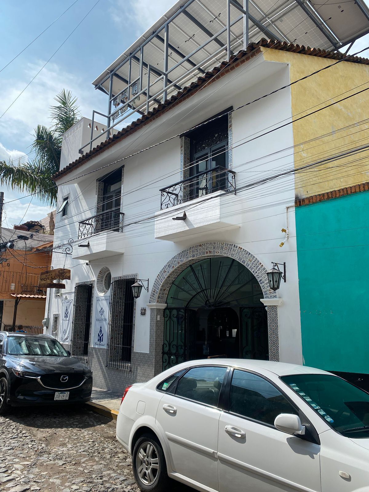 A two-story building with a white facade, a balcony, and a green awning.