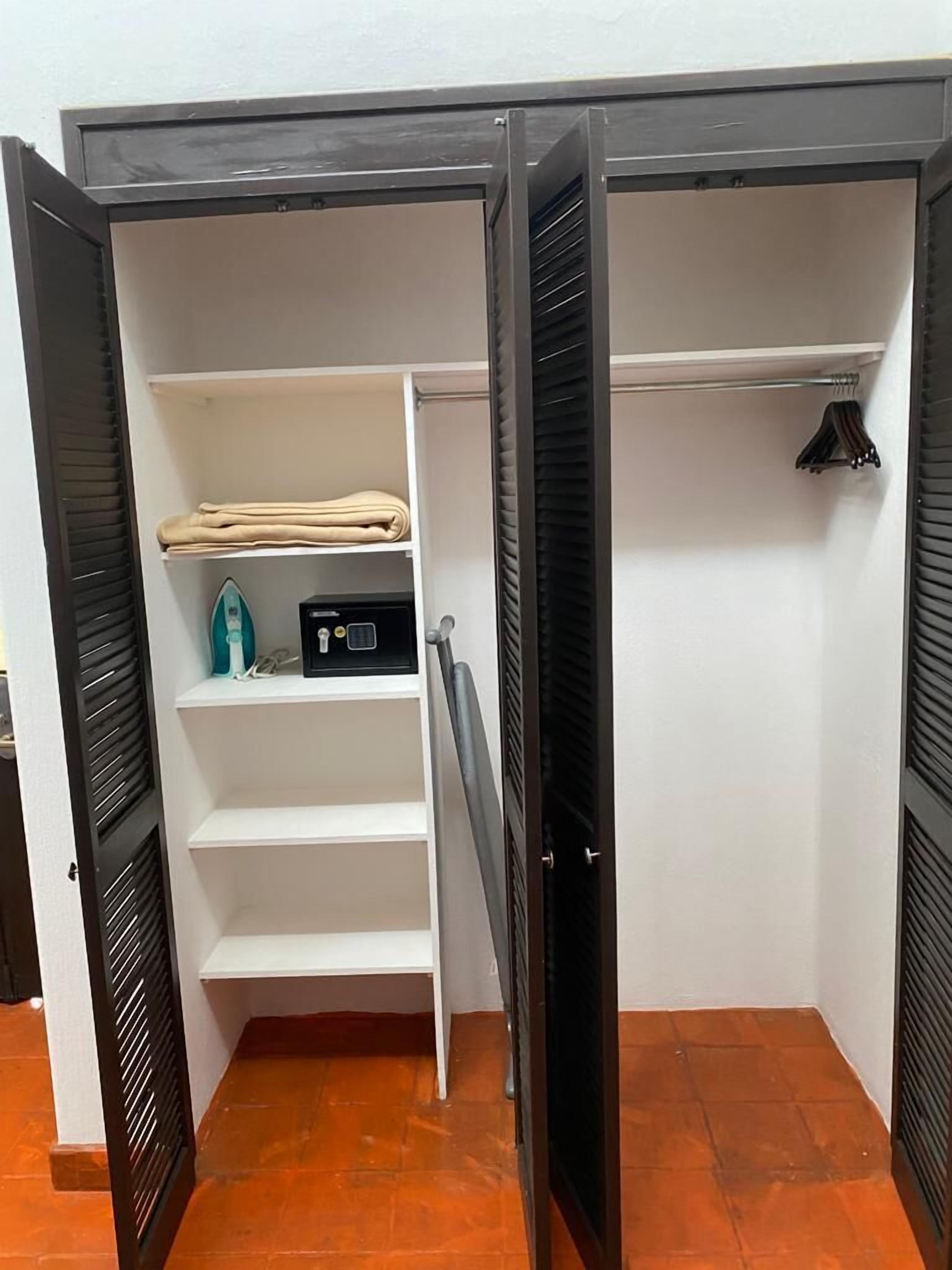 A walk-in closet with open doors, featuring shelves, a hanging rack, and a folded item on the top shelf.
