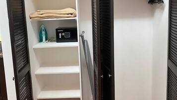 A walk-in closet with open doors, featuring shelves, a hanging rack, and a folded item on the top shelf.