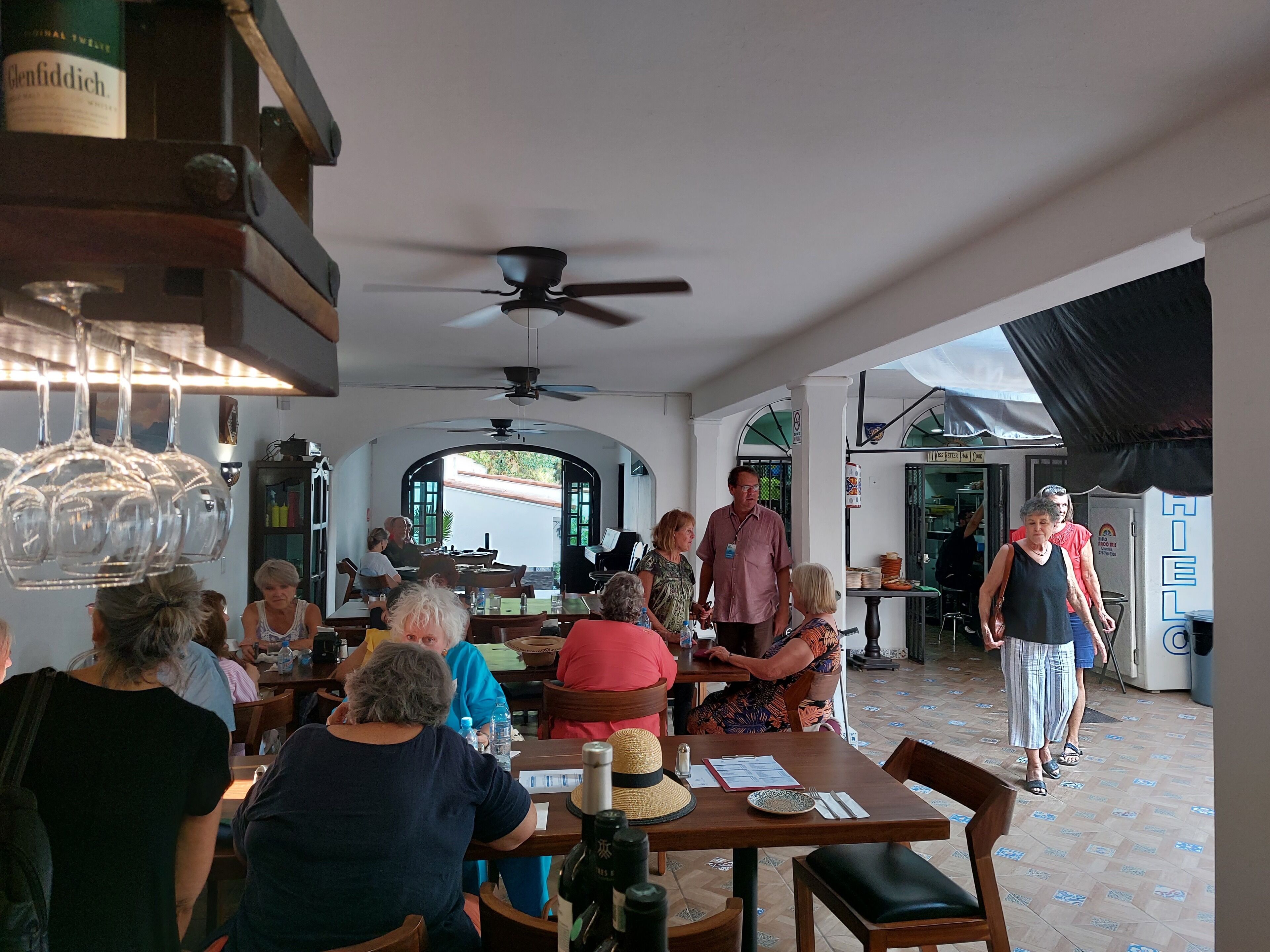 Un restaurante con zona de comedor, mesas, sillas y un ventilador de techo.