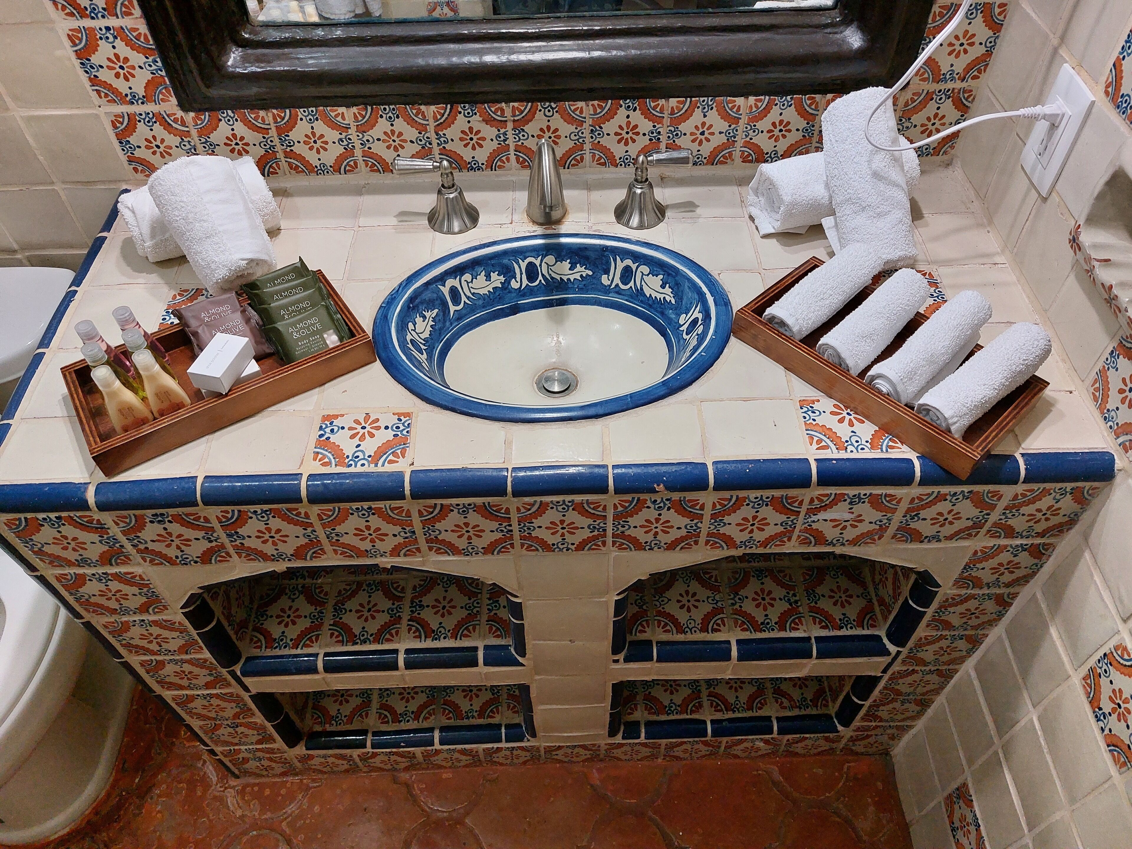 A bathroom with a blue ceramic sink, two towel racks, and a tray with toiletries.
