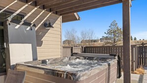 Un jacuzzi bajo una pérgola de madera con una silla cerca.
