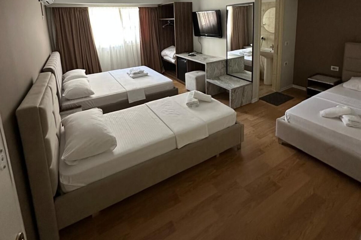 A hotel room with two beds, a desk, a TV, and a bathroom.