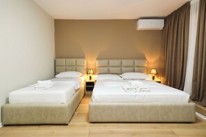 A hotel room with two beds, a headboard, bedside lamps, a flat-screen TV, and an air conditioning unit.
