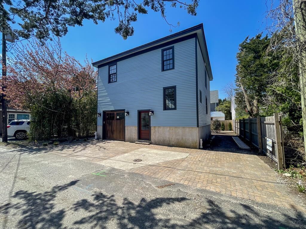 A two-story house with a garage, a paved driveway, and a wooden fence.