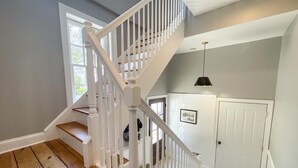 A staircase with white railings leading to a landing with a door and a framed picture. - 905 Page Street Cape May (Cape May)