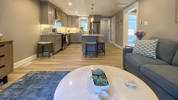 A modern kitchen with a central island, a dining area, and a living room with a sofa and coffee table. - 905 Page Street Cape May (Cape May)