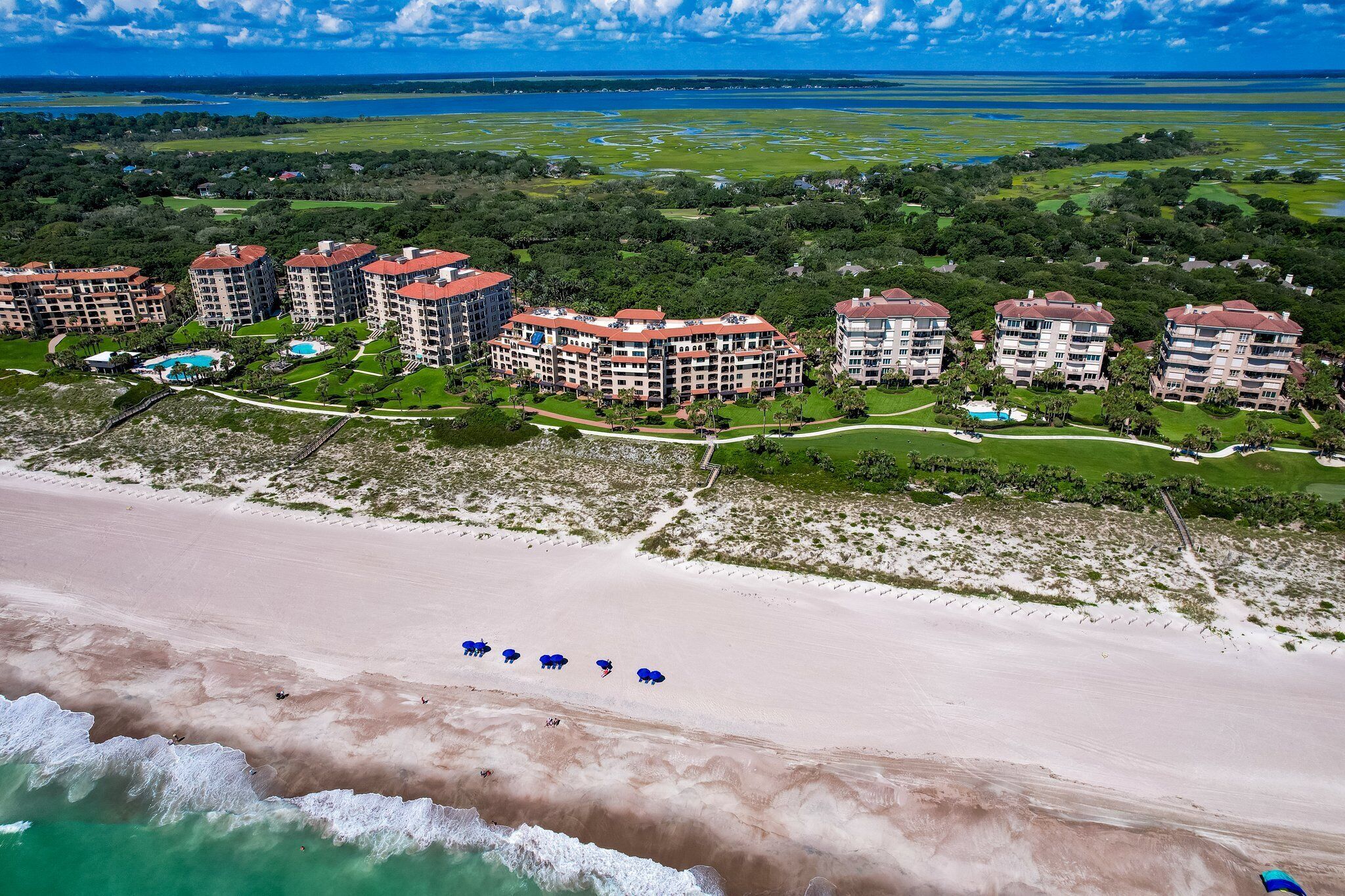 Ein Hotel an der Küste mit mehreren Gebäuden, einem Strand und einem Golfplatz.