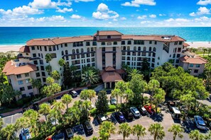 Un hotel a più piani con un cortile centrale, circondato da palme e un parcheggio.
