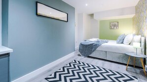 Een moderne slaapkamer met een bed, nachtkastje en een kamerbreed tapijt met een patroon.