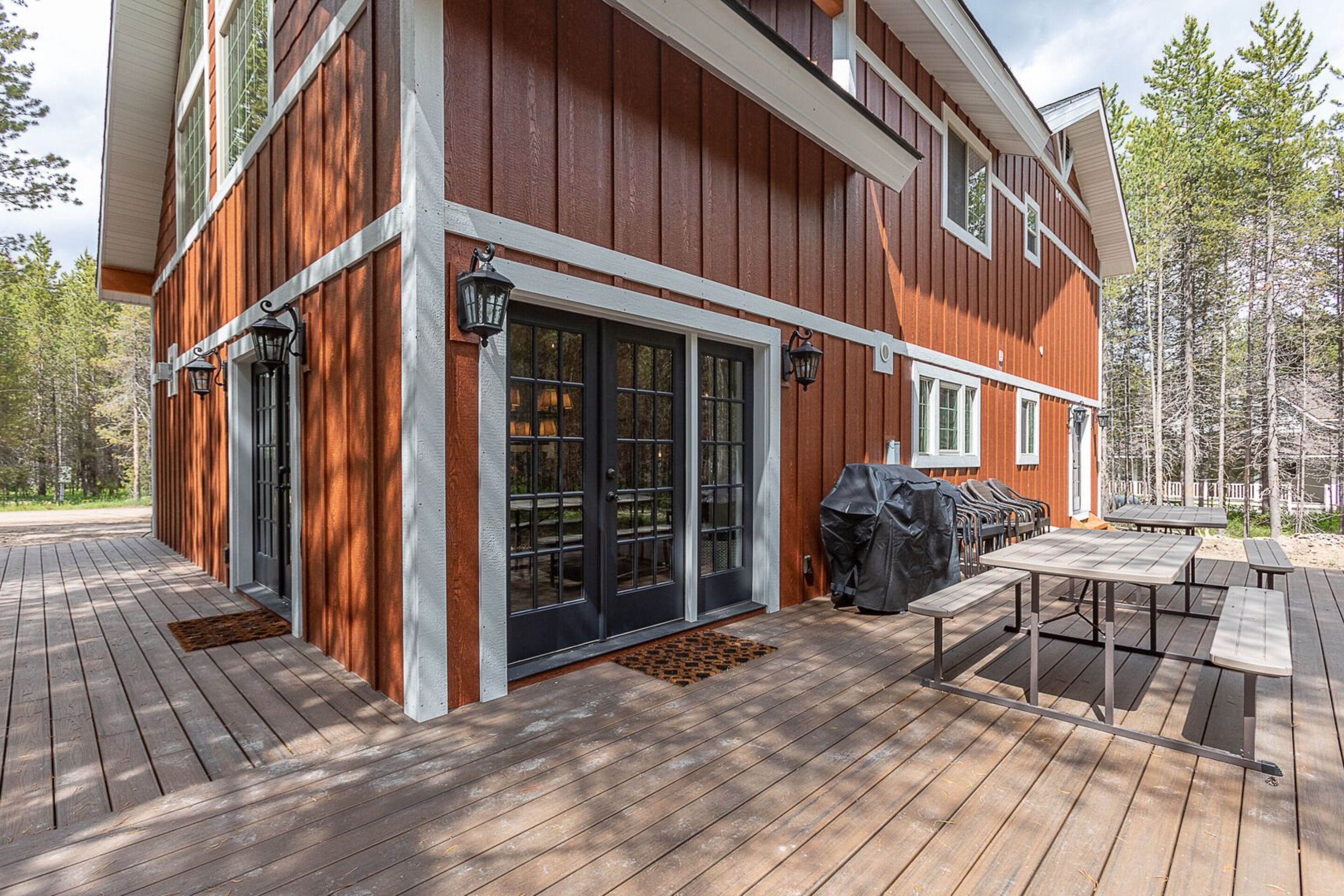 Un terrazzo in legno con posti a sedere all'aperto e un barbecue.