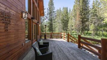 Relax on the deck with a view of the surrounding forest, featuring a large window and a door.