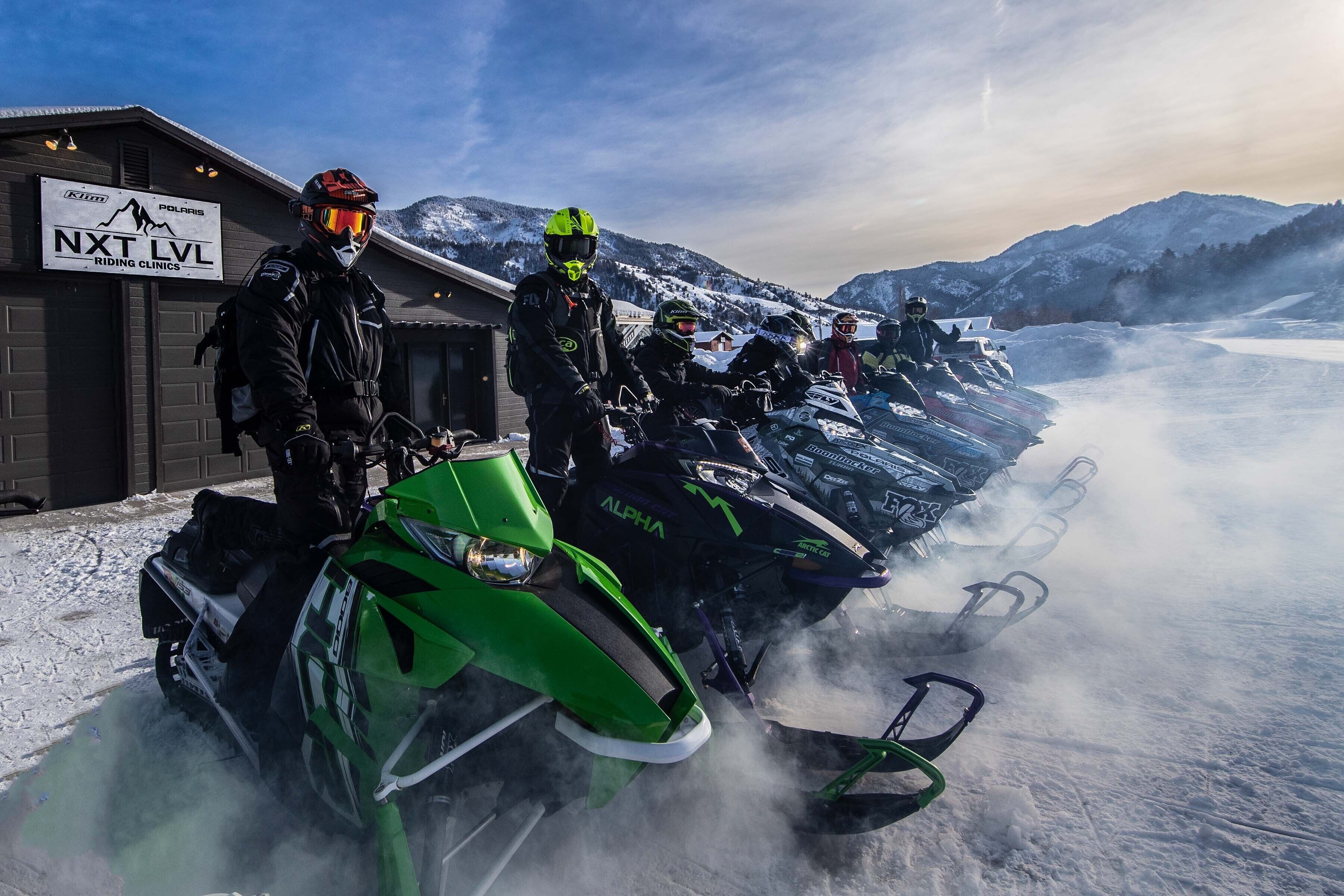 Uno snowmobile parcheggiato di fronte a un edificio con un cartello che recita 'NXT LVL RIDING CLINICS'.