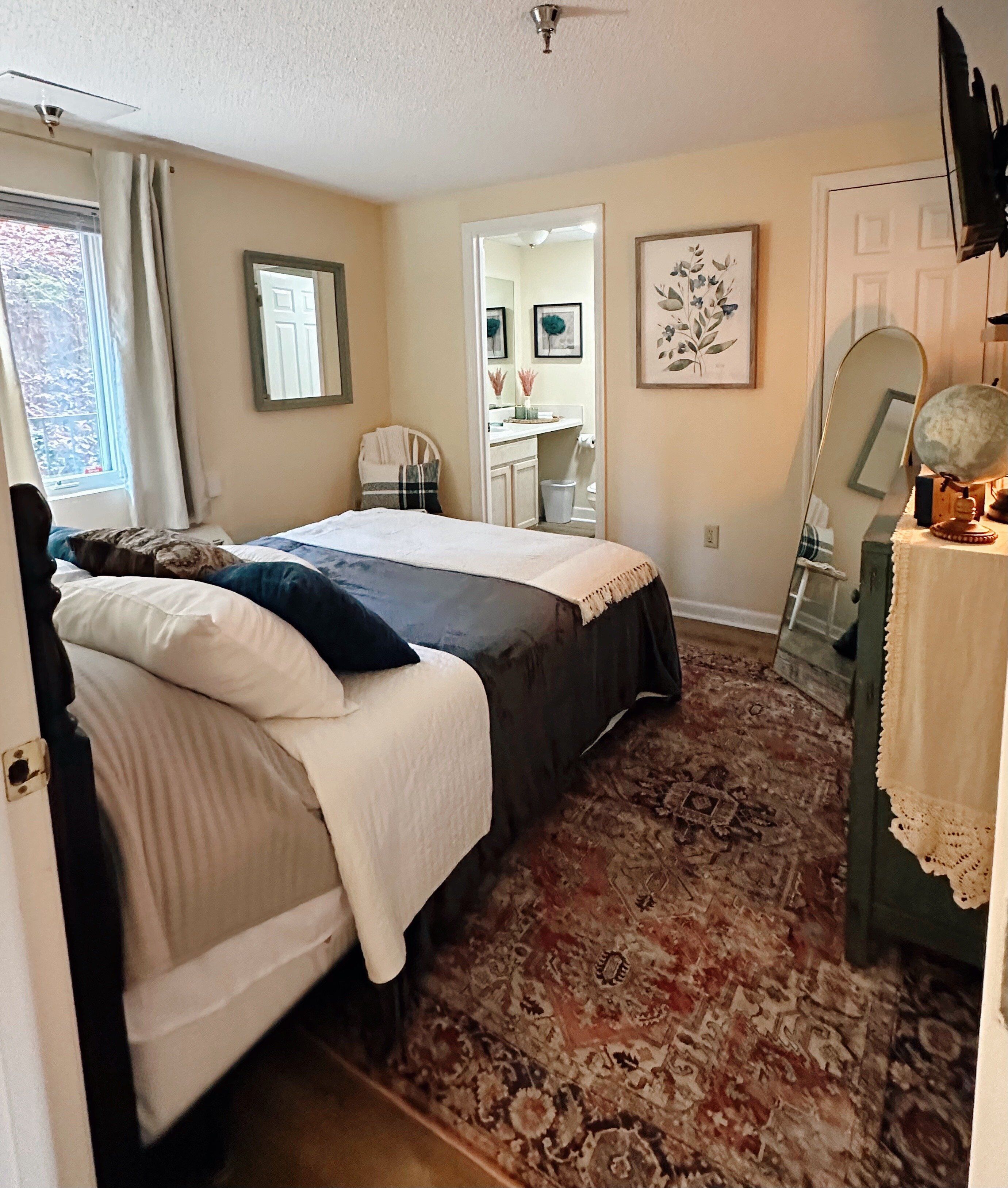Une chambre à coucher avec un lit, une commode, un miroir et un tapis.
