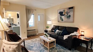 A living room with a sofa, armchair, coffee table, and a rug.
