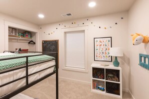 A child's bedroom with bunk beds, a bookshelf, a wall-mounted lamp, and a framed animal poster. - Whistling Moose (Island Park)