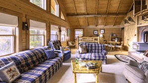 A cozy cabin interior with a wooden ceiling, plaid sofas, a dining area, and a fireplace. - Buffalo Bliss (Island Park)