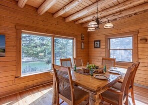 A wooden cabin with a dining table set for four, surrounded by chairs.