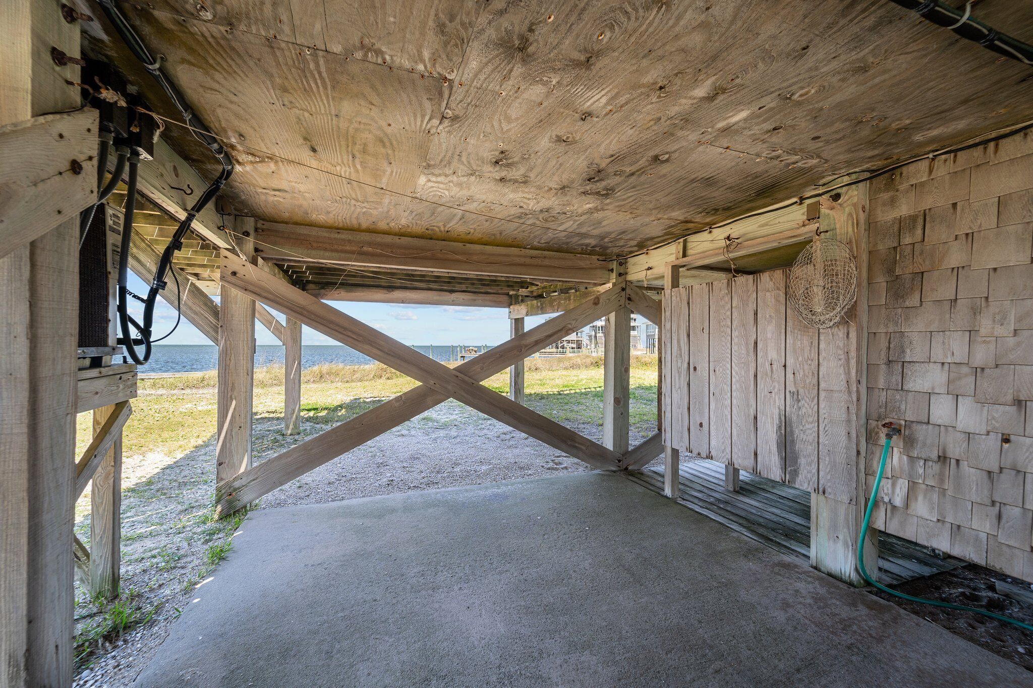 A wooden structure with a concrete floor, metal supports, and a view of the water.