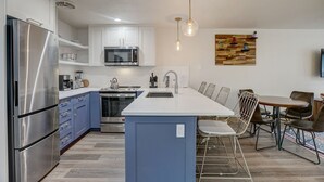 Una cocina moderna con electrodomésticos de acero inoxidable, una isla central y un comedor con sillas.