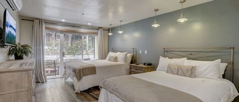 Quarto de hotel com duas camas, televisão, uma planta e vista para o exterior.