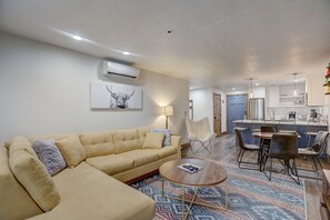 Un salon moderne avec un canapé beige, un tapis à motifs et un coin repas comprenant des chaises et une table.