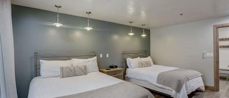 Quarto de hotel com duas camas, uma mesa de cabeceira e um lustre.