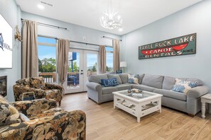 Ein Wohnzimmer mit grauem Sofa, floralen Sesseln, einem Couchtisch und Blick ins Freie.