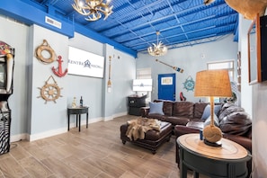 A living room with a blue ceiling, nautical decor, a brown leather sofa, and a lamp.