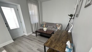 A living room with a sofa, a coffee table, and a wooden table. - The Merlot, minutes to Niagara's Falls, 3 bedrooms with Hottub and Sauna (Niagara Falls)