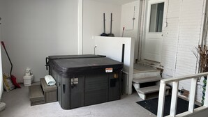 A compact room with a large black storage unit, a small table with a chair, a white door, and a staircase leading to an upper level. - The Merlot, minutes to Niagara's Falls, 3 bedrooms with Hottub and Sauna (Niagara Falls)