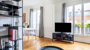 Un soggiorno moderno con un mobile TV nero, una televisione a schermo piatto e un'area pranzo con un tavolo e sedie bianche.