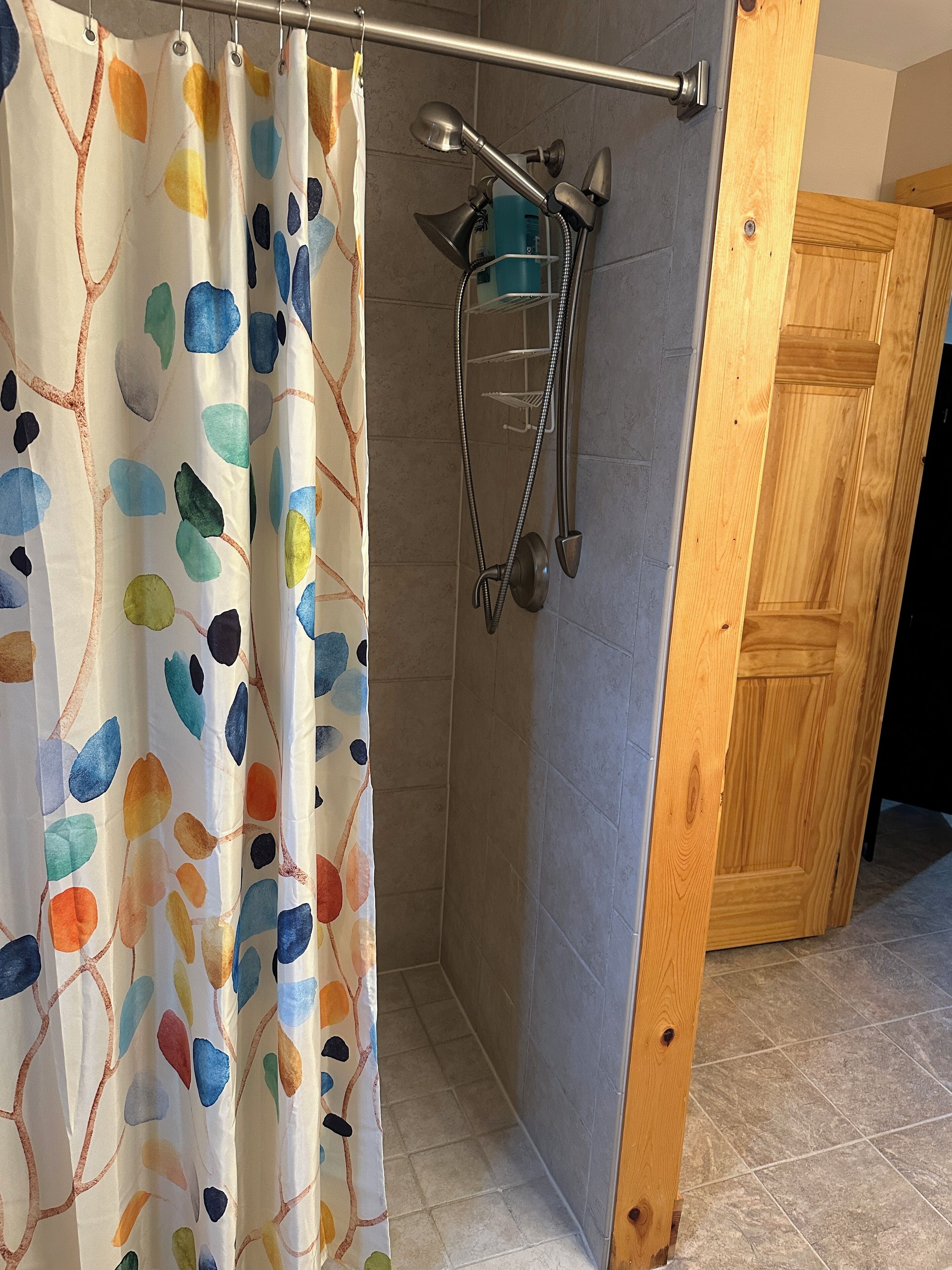 A shower area with a showerhead, handheld shower, and a shower caddy.