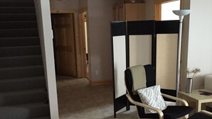 Een woonkamer met een bank, een stoel, een tafel, een lamp en een trap.