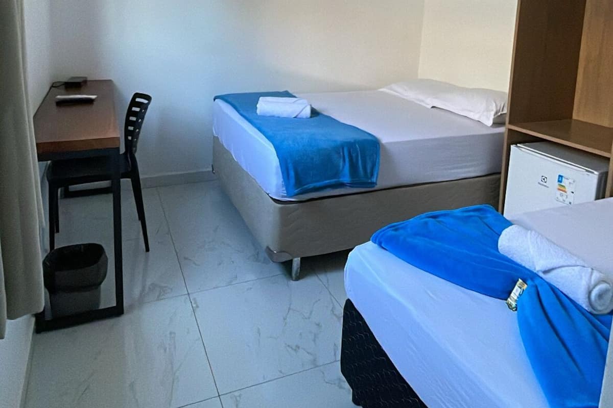 Una habitación pequeña y limpia con dos camas, un escritorio y una silla.