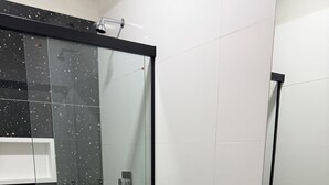 Een moderne badkamer met een douchecabine van glas, een toilet, een wastafel en een spiegel.