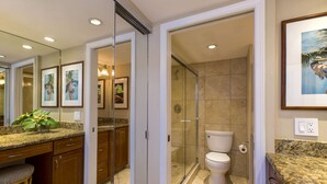 Une salle de bain moderne dotée d’une douche à parois de verre, de toilettes et d’un meuble-lavabo avec un plan de travail en granit.