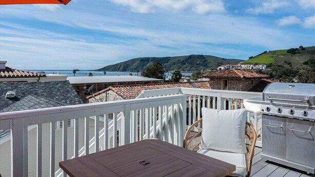 Un balcón con vistas al mar, una parrilla y una barandilla blanca.