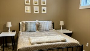 Un dormitorio con cama, dos mesitas de noche, ventilador de techo e imágenes enmarcadas en la pared.