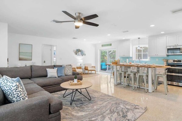 A modern living room with a sectional sofa, a coffee table, and a ceiling fan.