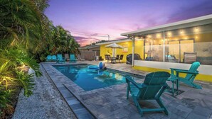 A swimming pool with lounge chairs and a covered patio area.