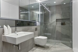 A modern bathroom with a large sink, toilet, and glass-enclosed shower. - Elegant retreat in Wynyard Quarter (Auckland)