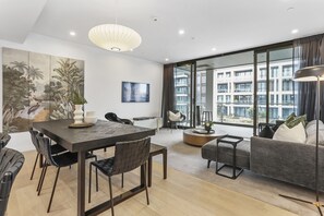 A modern living room with a dining area, large windows, and a view of a building. - Elegant retreat in Wynyard Quarter (Auckland)