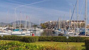 Un port de plaisance où sont amarrés de nombreux bateaux, une étendue d’eau et, au fond, un ensemble de bâtiments.